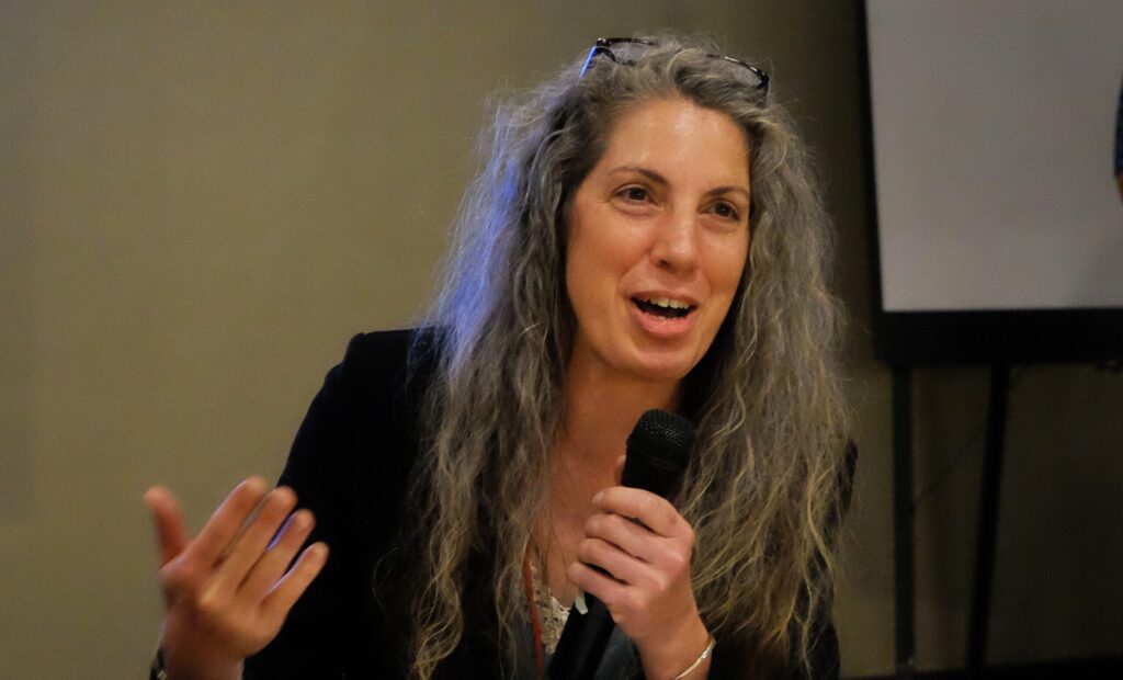 Dawn is talking into a microphone at a roundtable